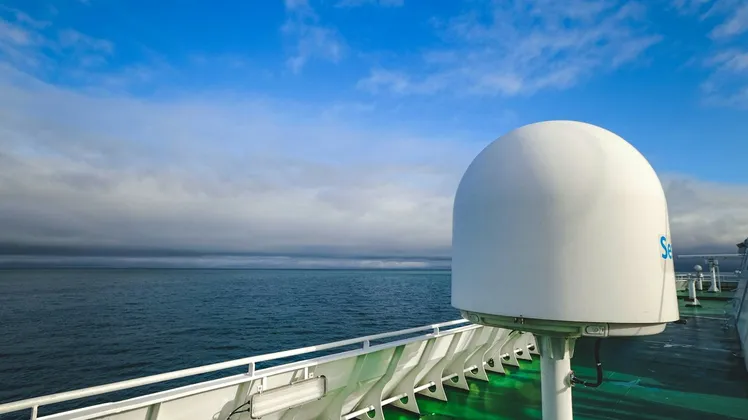 A maritime VSAT satellite dome on a ship's deck, overlooking the open sea.